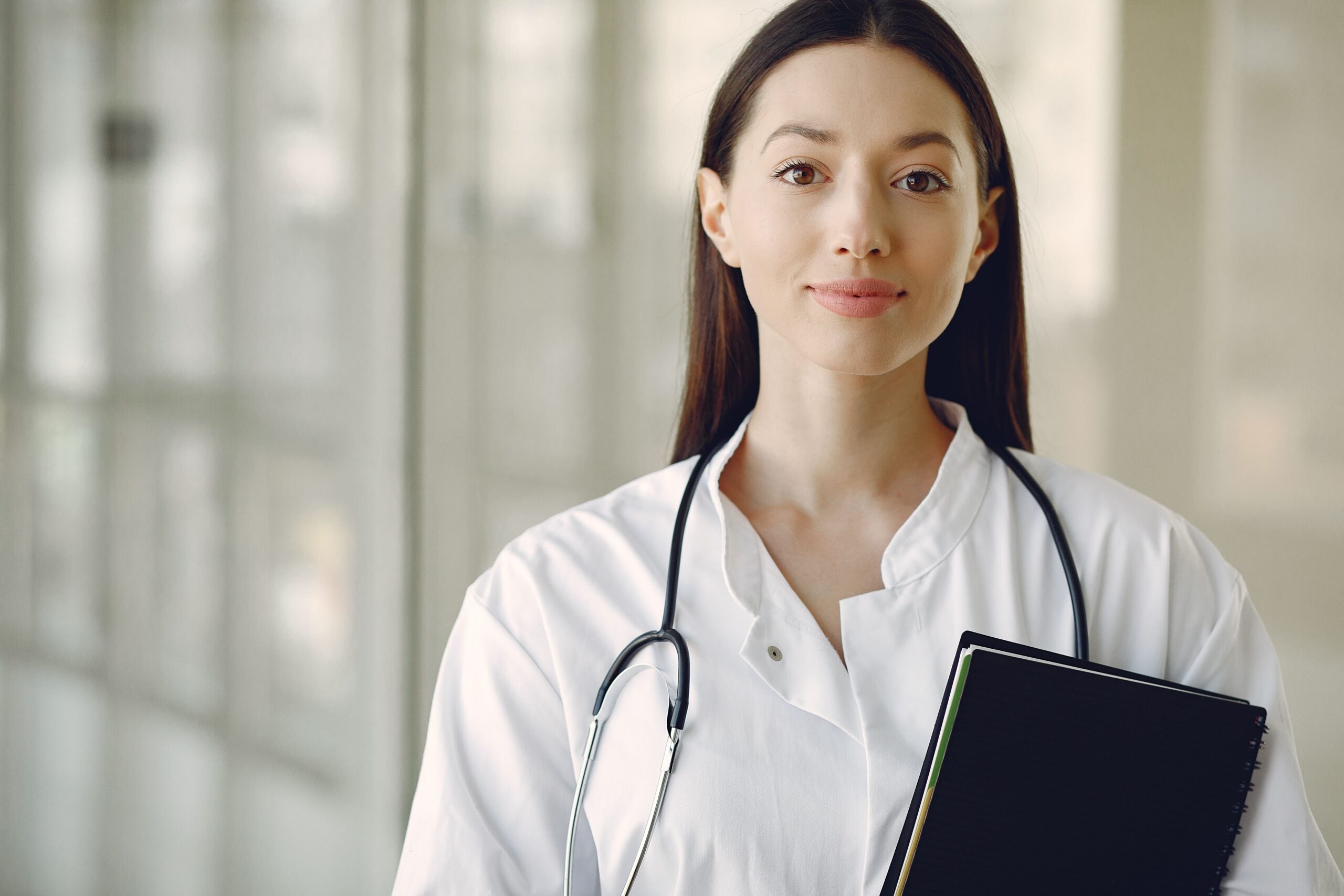 Confident young female doctor in a white coat with stethoscope.