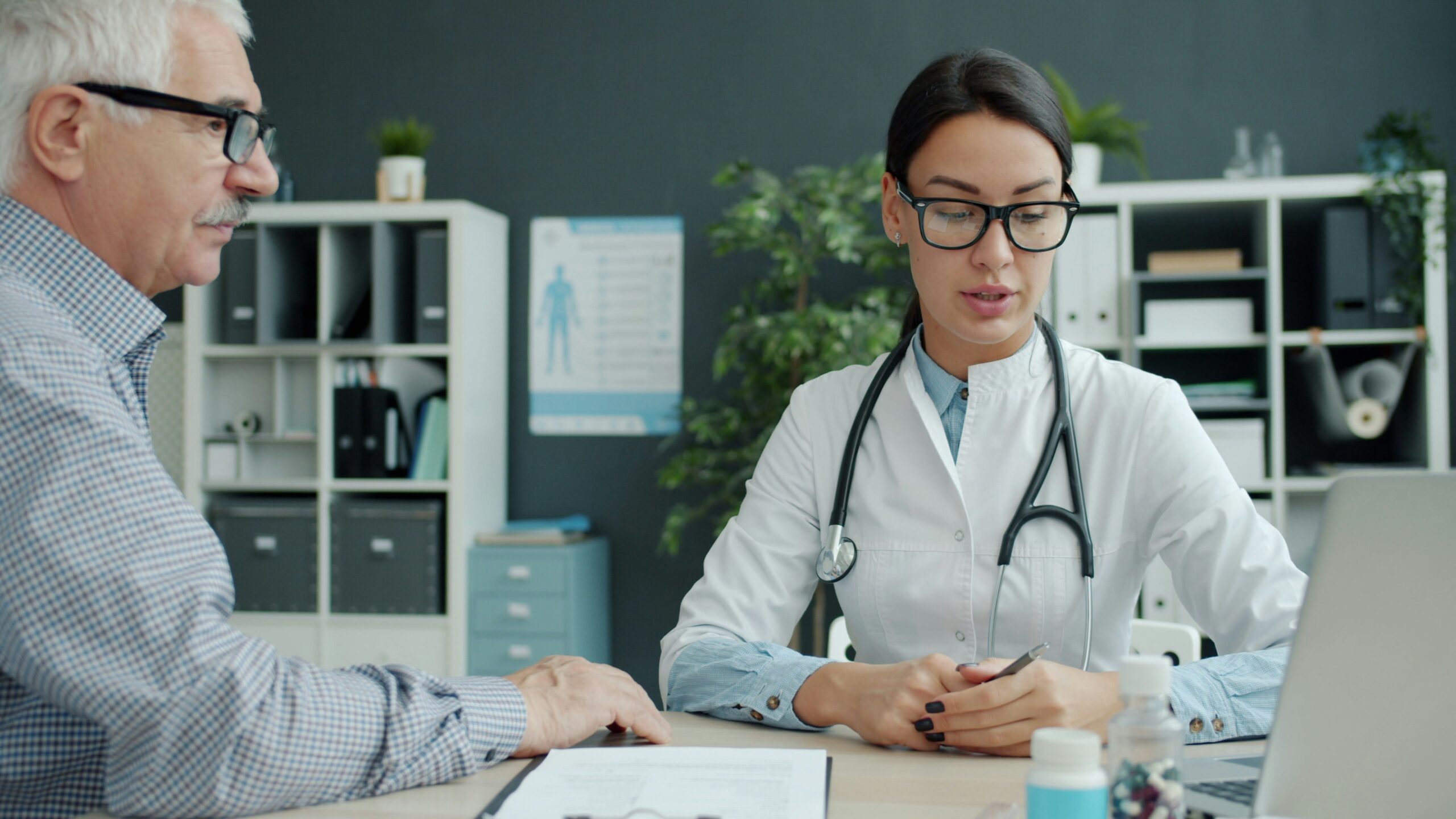 Friendly female doctor talking to an elderly patient holding hand expressing care.